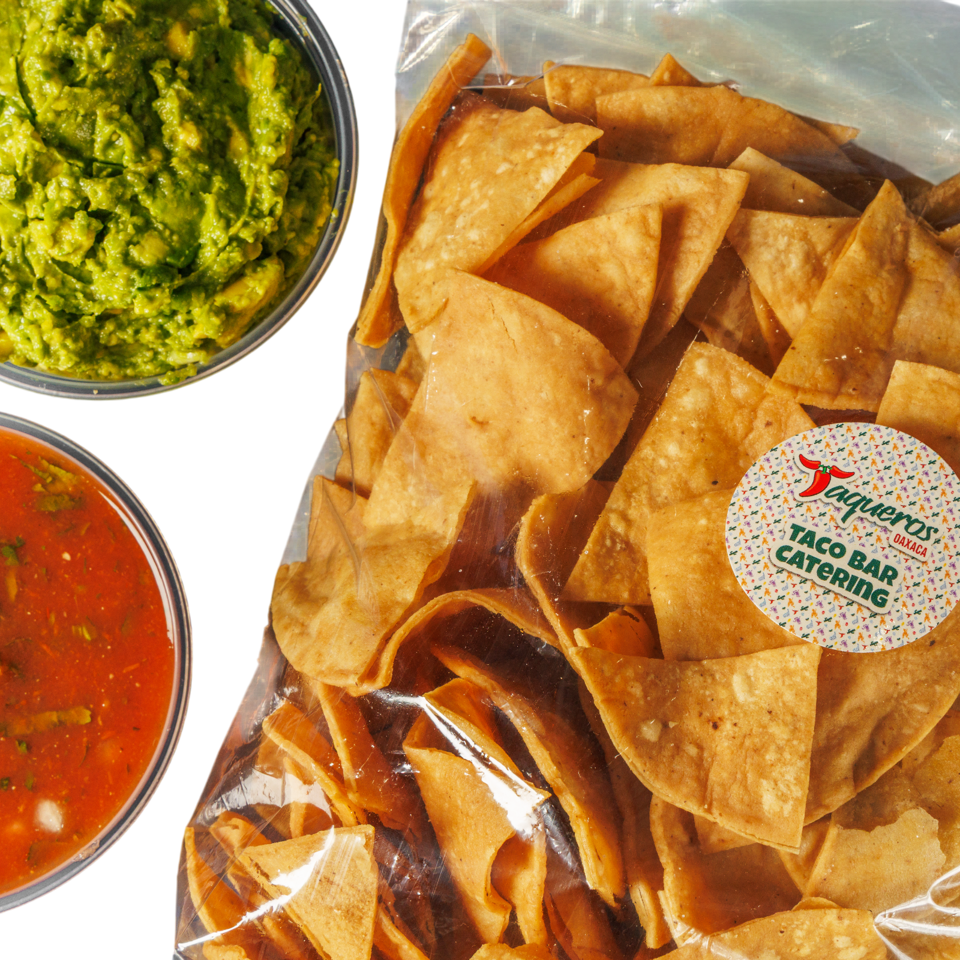 Bag of tortilla chips with guacamole and red salsa, labeled Aguaceros Oaxaca Taco Bar Catering.