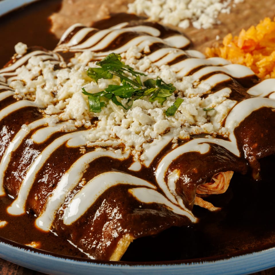 Taqueros Mexican Restaurant's enchiladas with rich mole sauce, crema, cotija cheese, and cilantro.