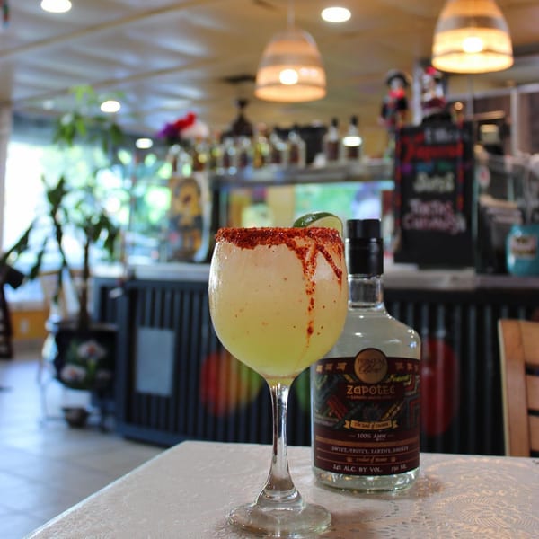 A chili-rimmed margarita and a bottle of Zapotec tequila on a table at Taqueros Mexican Restaurant.