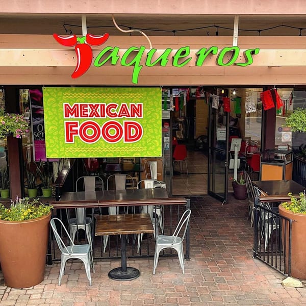 The exterior of Taqueros Mexican Restaurant with outdoor seating and a "Mexican Food" banner.