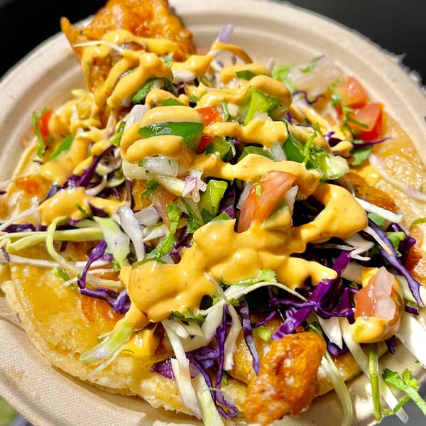 Close-up of a Taqueros Mexican Restaurant taco with fried fish, cabbage, salsa, and creamy sauce.