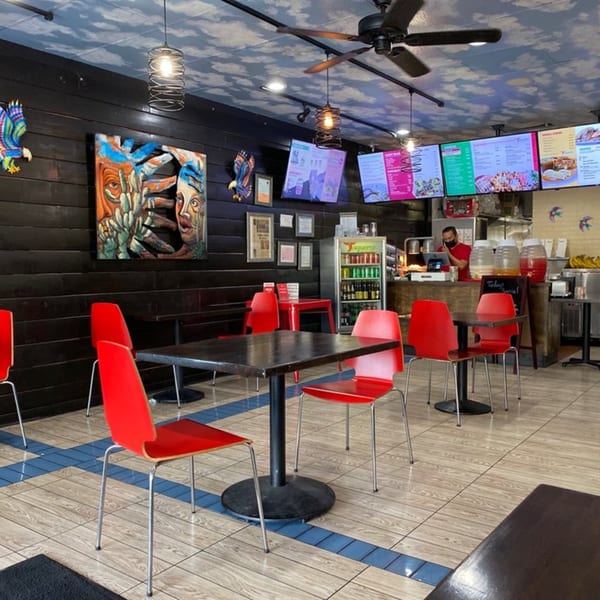 Interior of Taqueros Mexican Restaurant with red chairs, dark tables, and a cloud-painted ceiling.